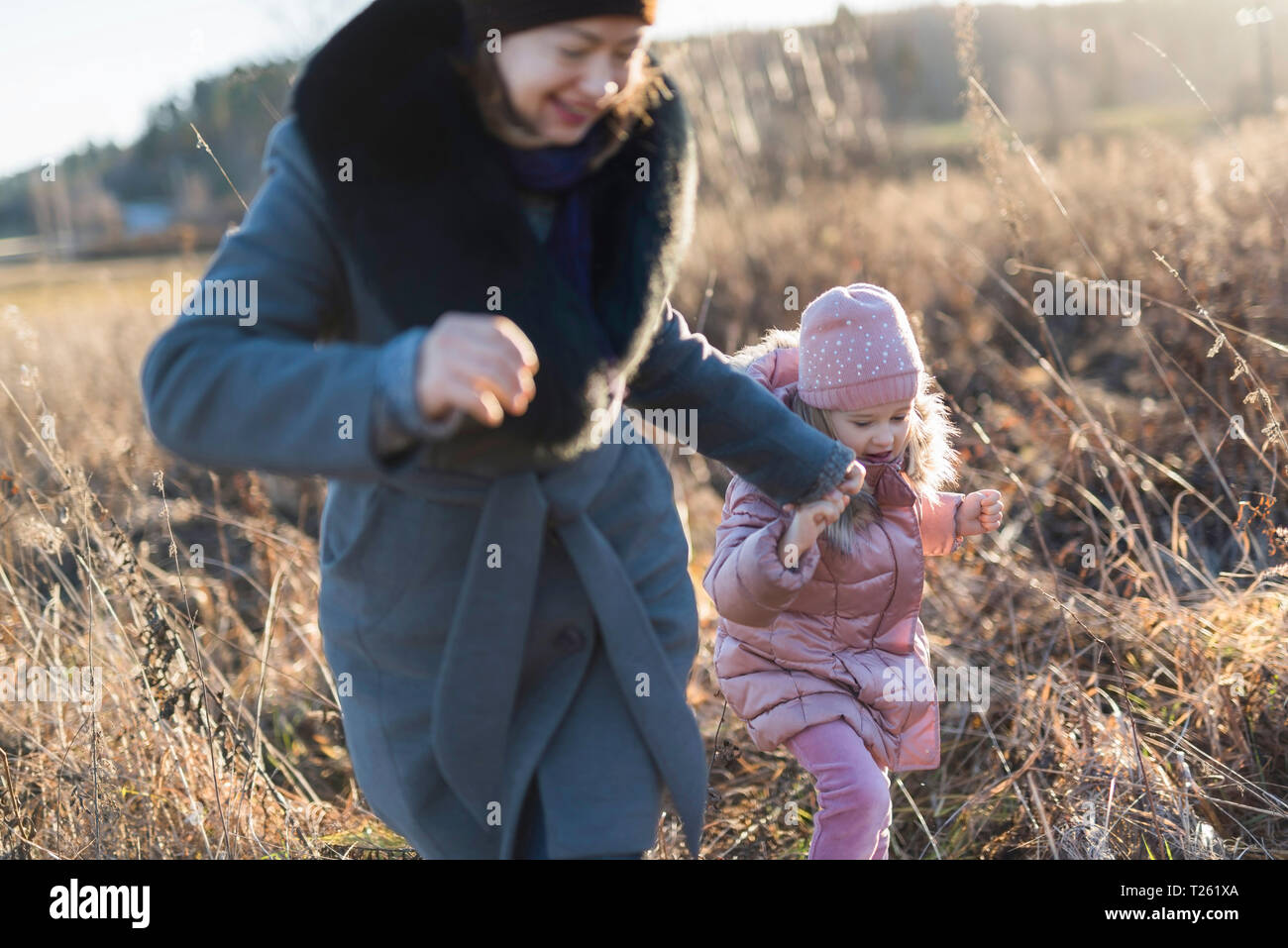 Bambina in esecuzione mano nella mano con la mamma sul prato autunnale a ora d'Oro Foto Stock