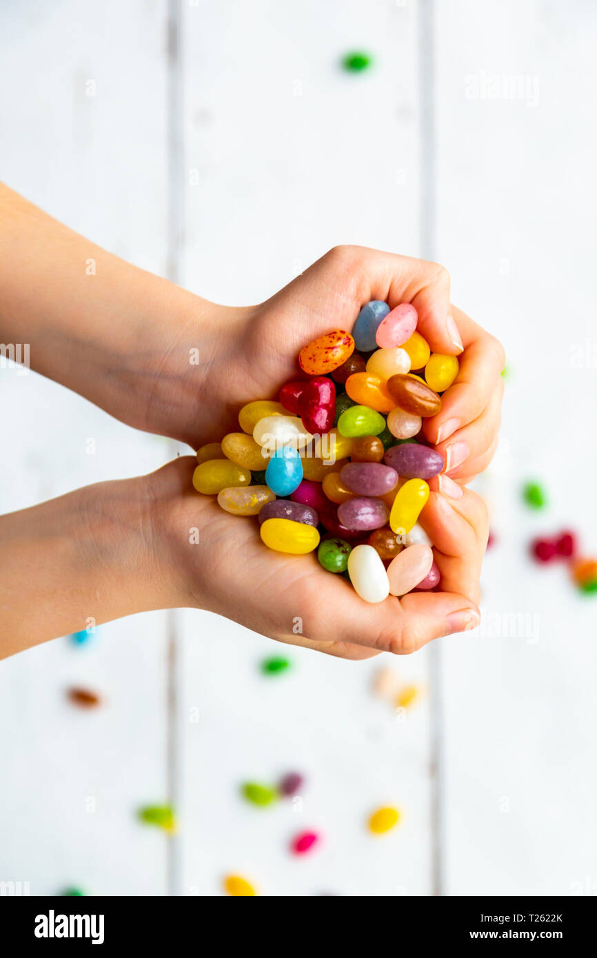 Colorate jellybeans dolce in mano, formando un cuore Foto Stock
