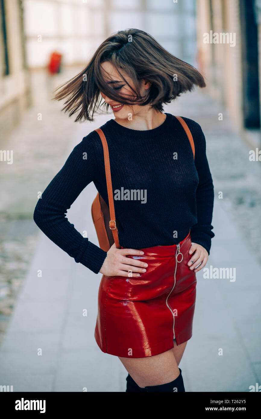 Sorridente giovane donna indossa il brevetto rosso gonna in pelle con  cerniera lampo nel lanciare i suoi capelli Foto stock - Alamy
