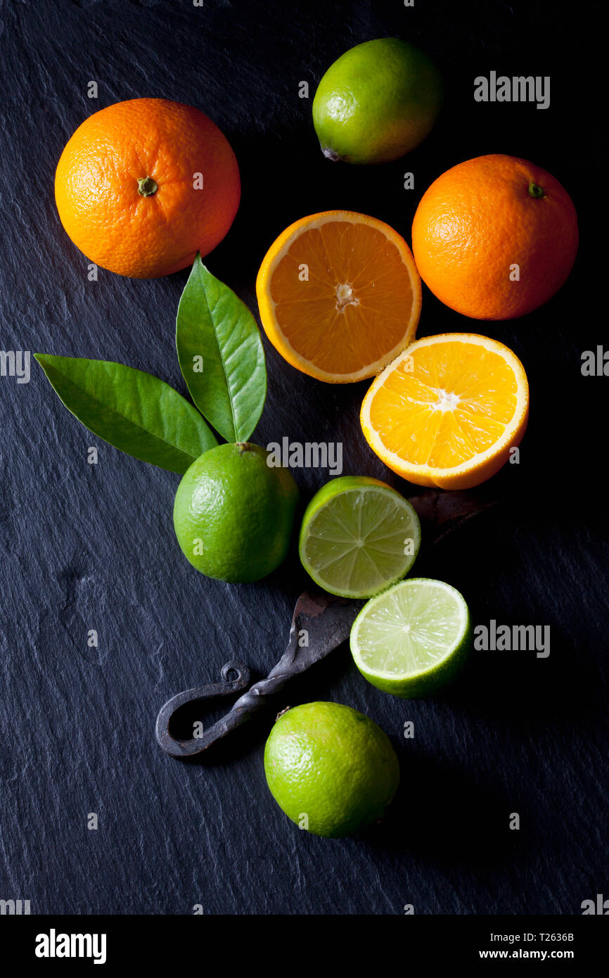 Fette di lime e arance con un vecchio coltello Foto Stock