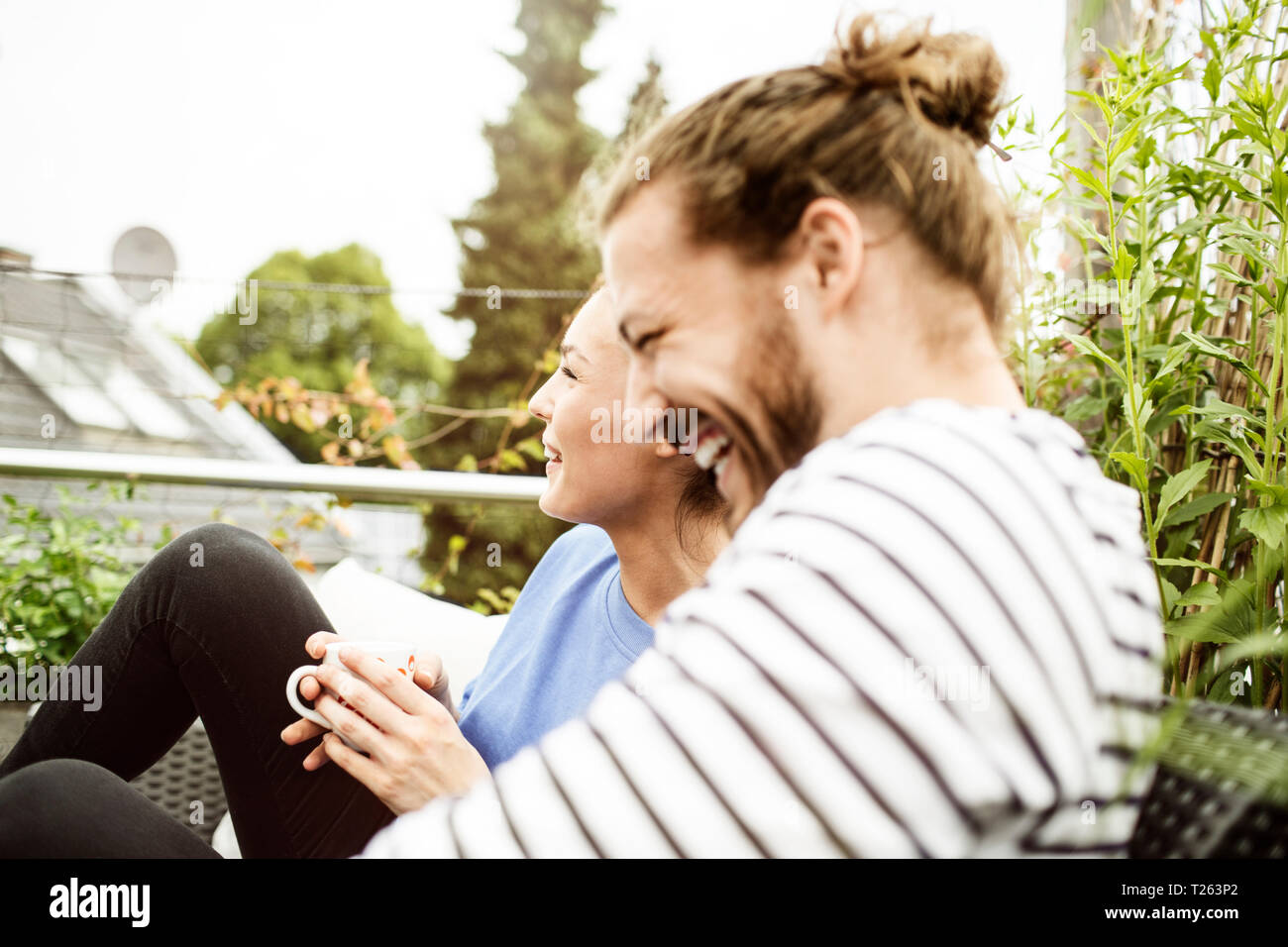 Coppia giovane rilassante sul proprio balcone, bere caffè Foto Stock