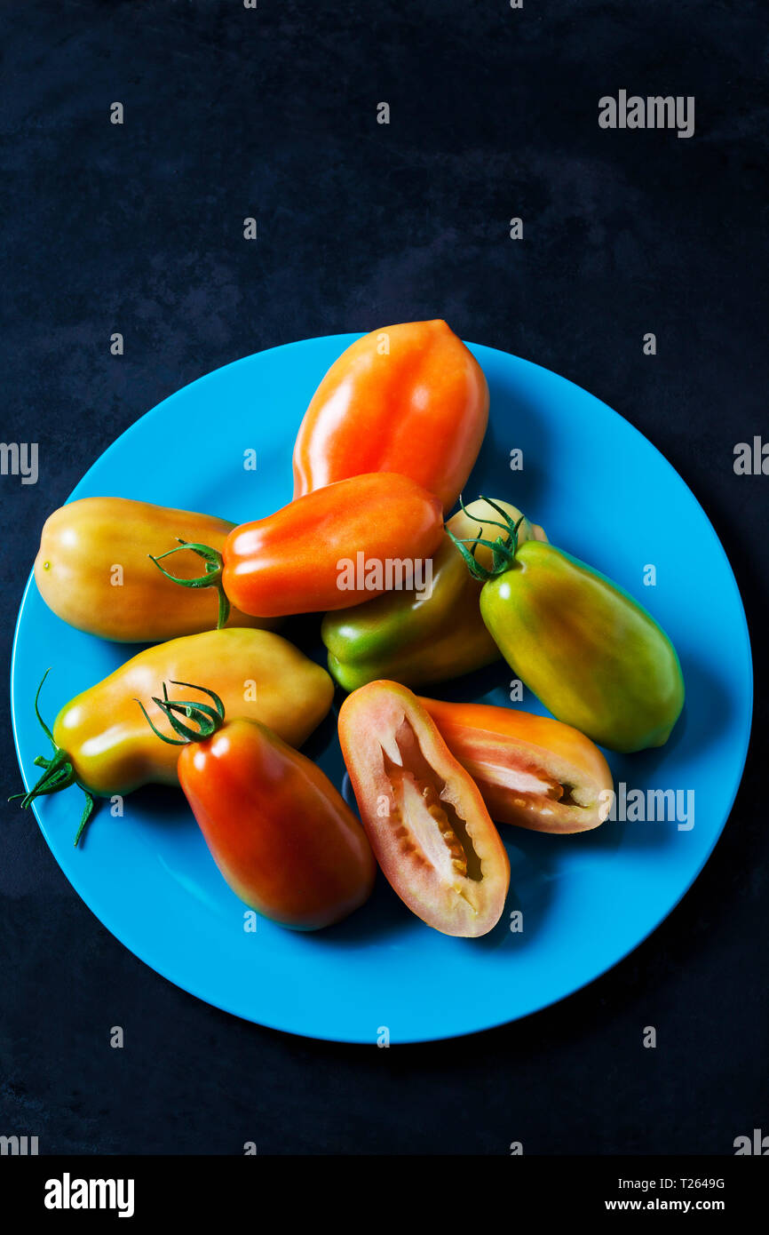 Intero e fette di pomodoro San Marzano su luce piastra di blu Foto Stock