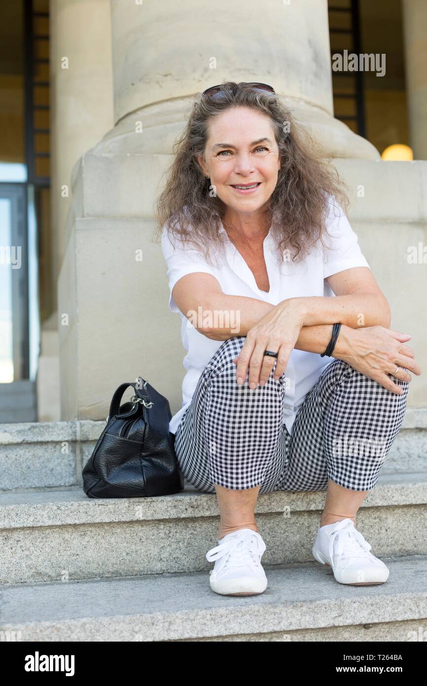 Ritratto di sorridere donna matura seduti sulle scale in estate Foto Stock
