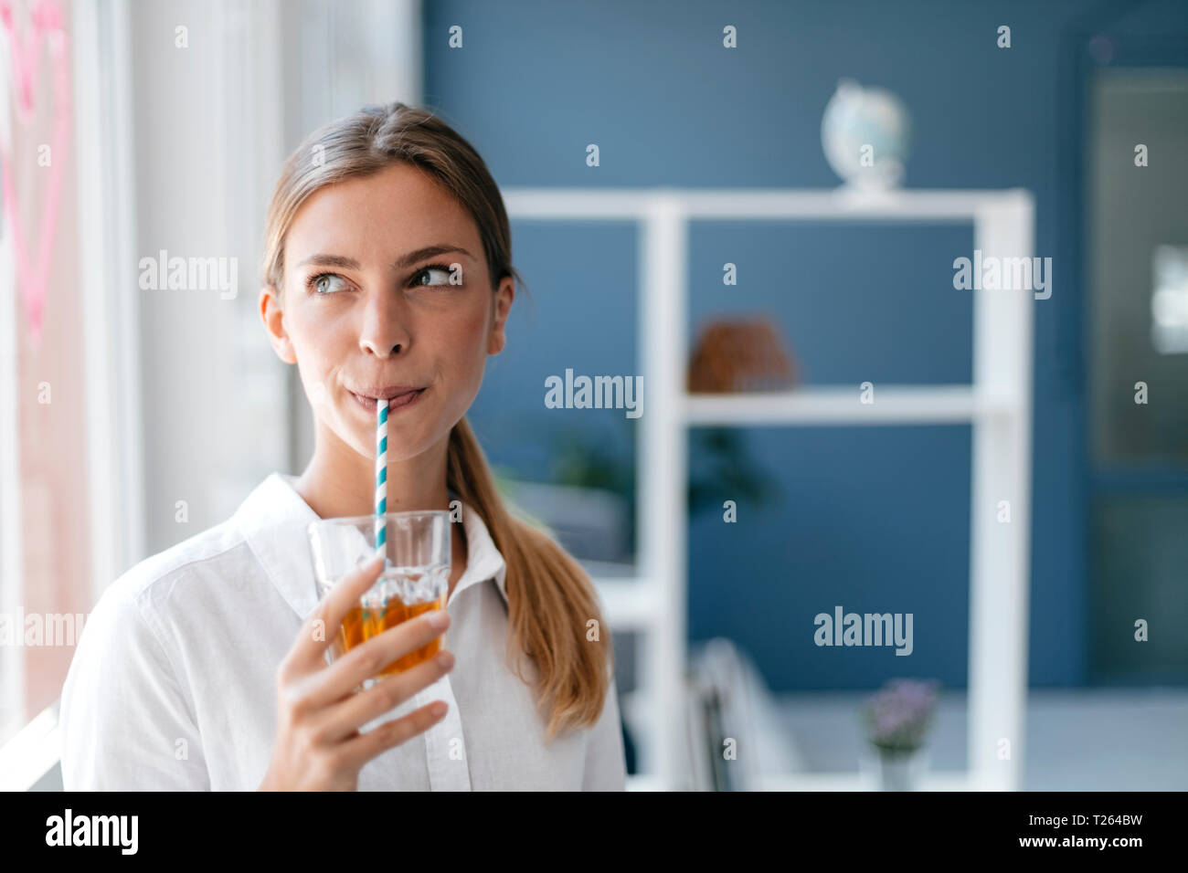 Giovane donna bere il tè con una paglia Foto Stock