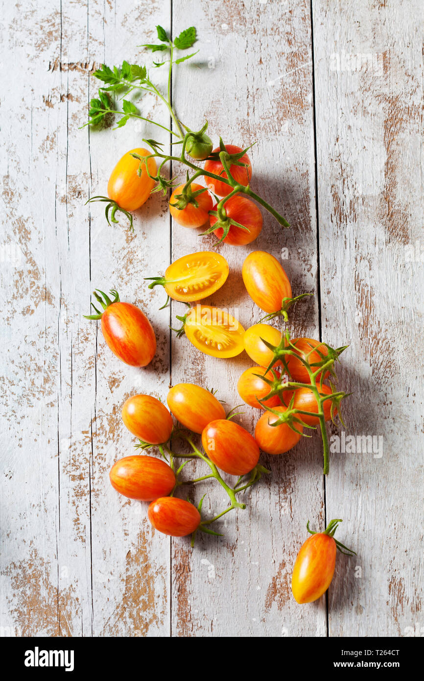 Intero e fette di pomodoro cocktail "artigiano arrossire Tiger" su legno Foto Stock