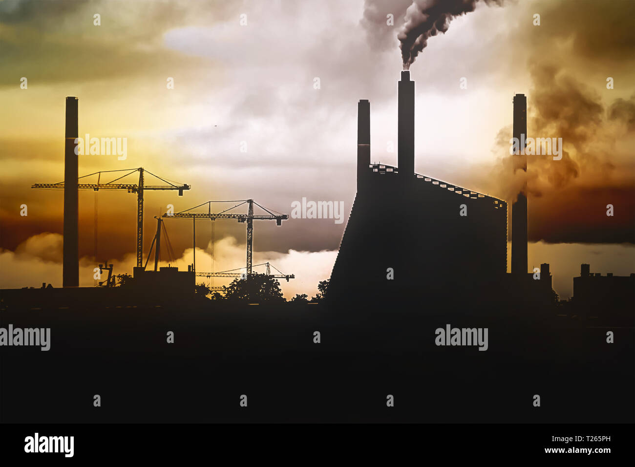 Concetto di un ambiente inquinato - un panorama della città al tramonto con la silhouette di una fabbrica e gru, e smog da camini. Foto Stock