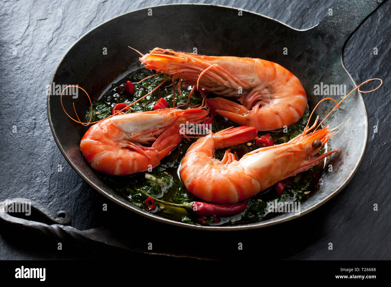 Gamberi con hernbs, peperoncino e aglio in padella di ferro Foto Stock