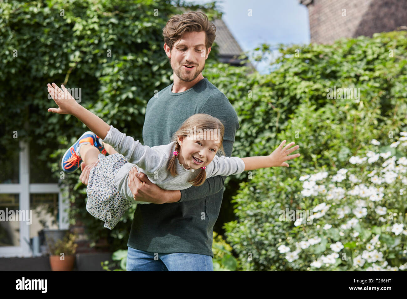 Padre Felice giocando con la figlia nel giardino della loro casa Foto Stock