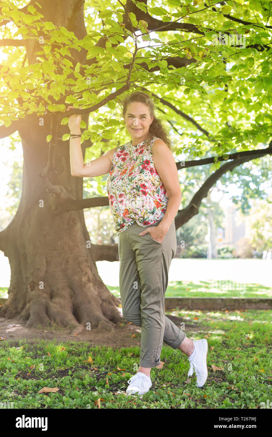 Ritratto di sorridere donna matura in un parco indossando top con disegno floreale Foto Stock