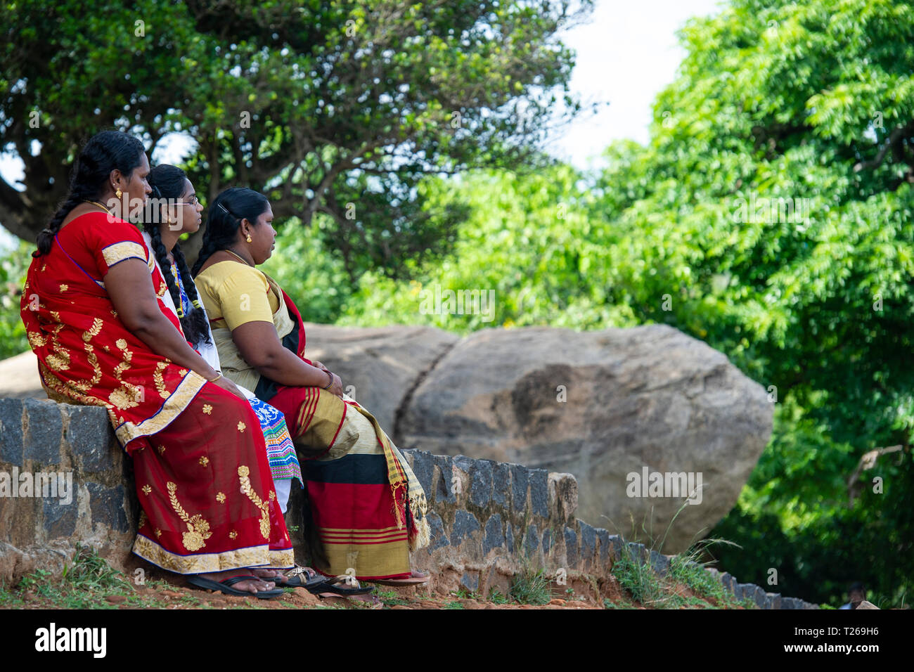 Eleganza presso i monumenti di Mahabalipuram vicino a Chennai, India come tre giovani si siedono in campagna Foto Stock