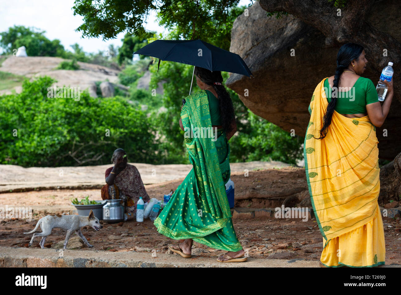 Eleganza presso i monumenti di Mahabalipuram vicino a Chennai, India come donne passeggiata in campagna, proteggersi dal sole con un ombrellone Foto Stock