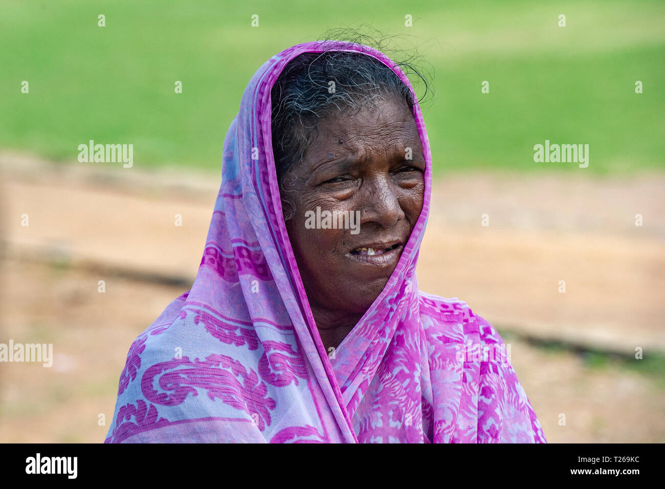 Una vecchia signora in India, con una rosa sari e denti mancanti Foto Stock