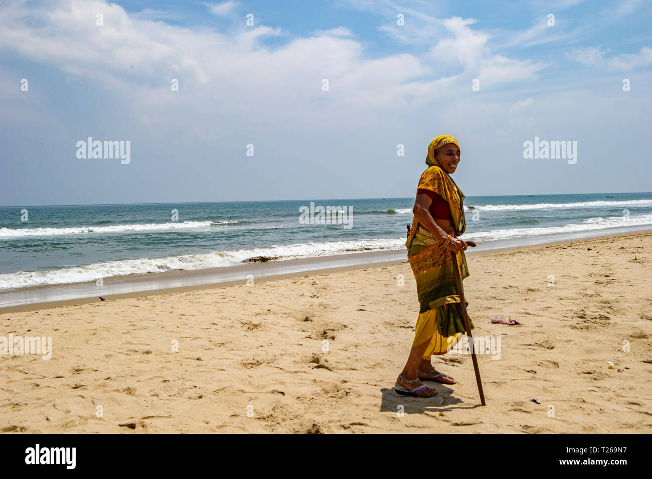 Una vecchia signora con un bastone da passeggio gode la tranquillità e la pace del mare a Marina Beach, con il golfo del Bengala a Chennai, India Foto Stock