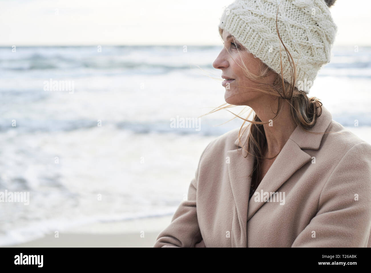 Spagna, Menorca, profilo di senior donna che indossa wooly hat sulla spiaggia in inverno Foto Stock