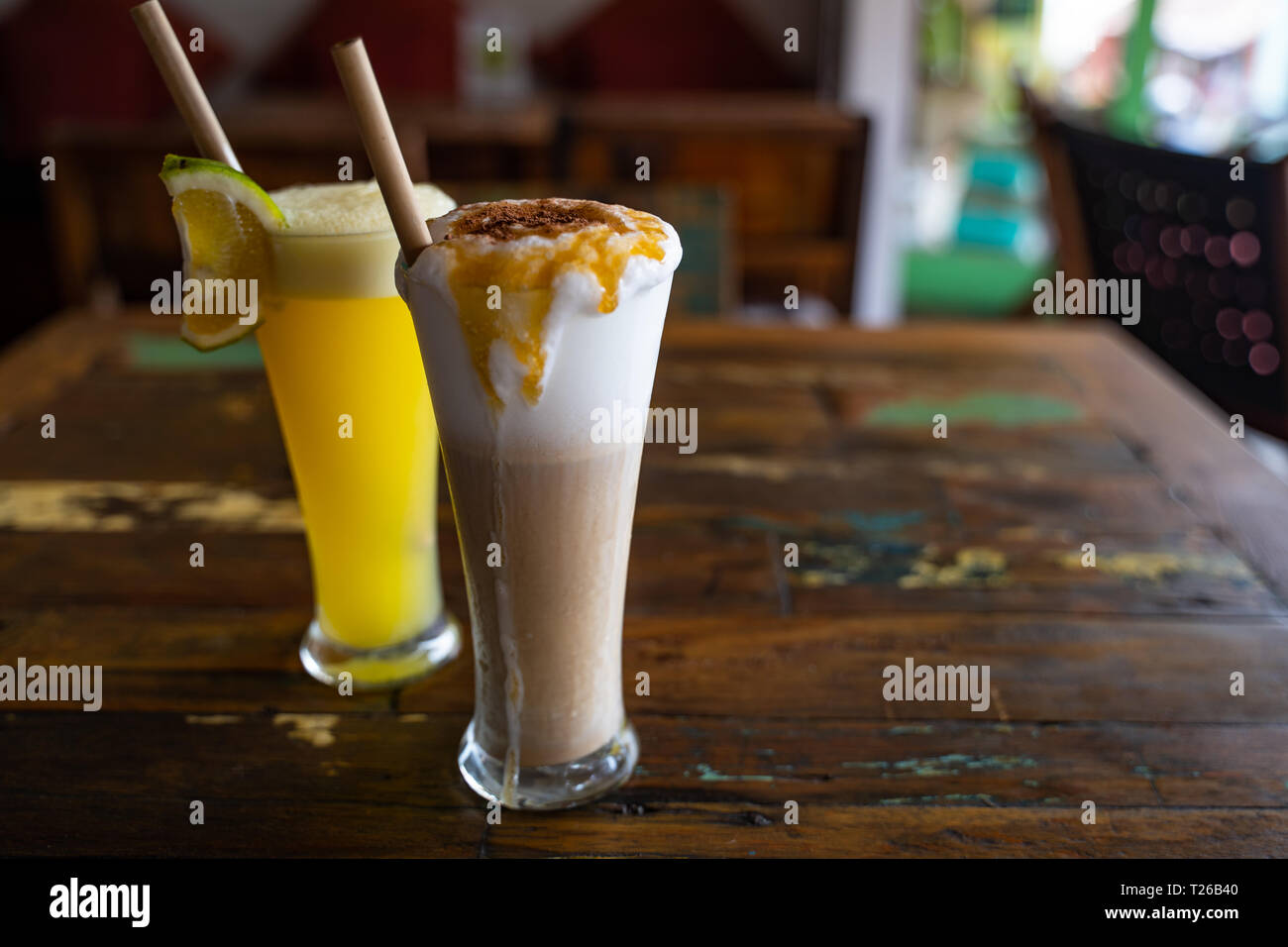 Spremuta di arancia fresca e il cioccolato frullato in bicchieri alti con una cannuccia su legno tabella vintage in cafe. Spazio di copia Foto Stock