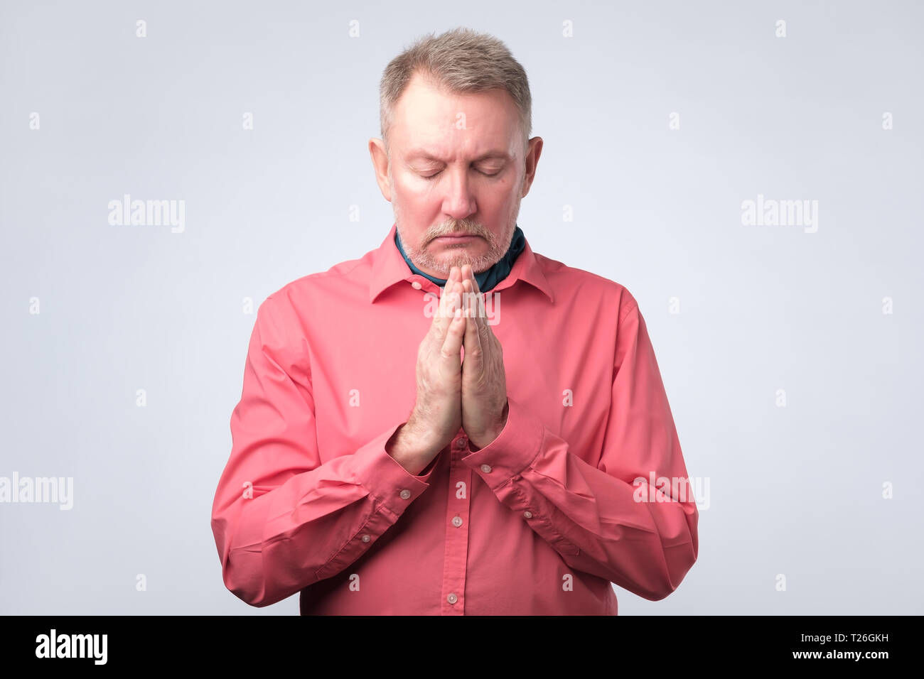 Senior vecchio uomo europeo mettere le mani insieme nella preghiera o nella meditazione, guardando la calma, in attesa di tutti i migliori Foto Stock