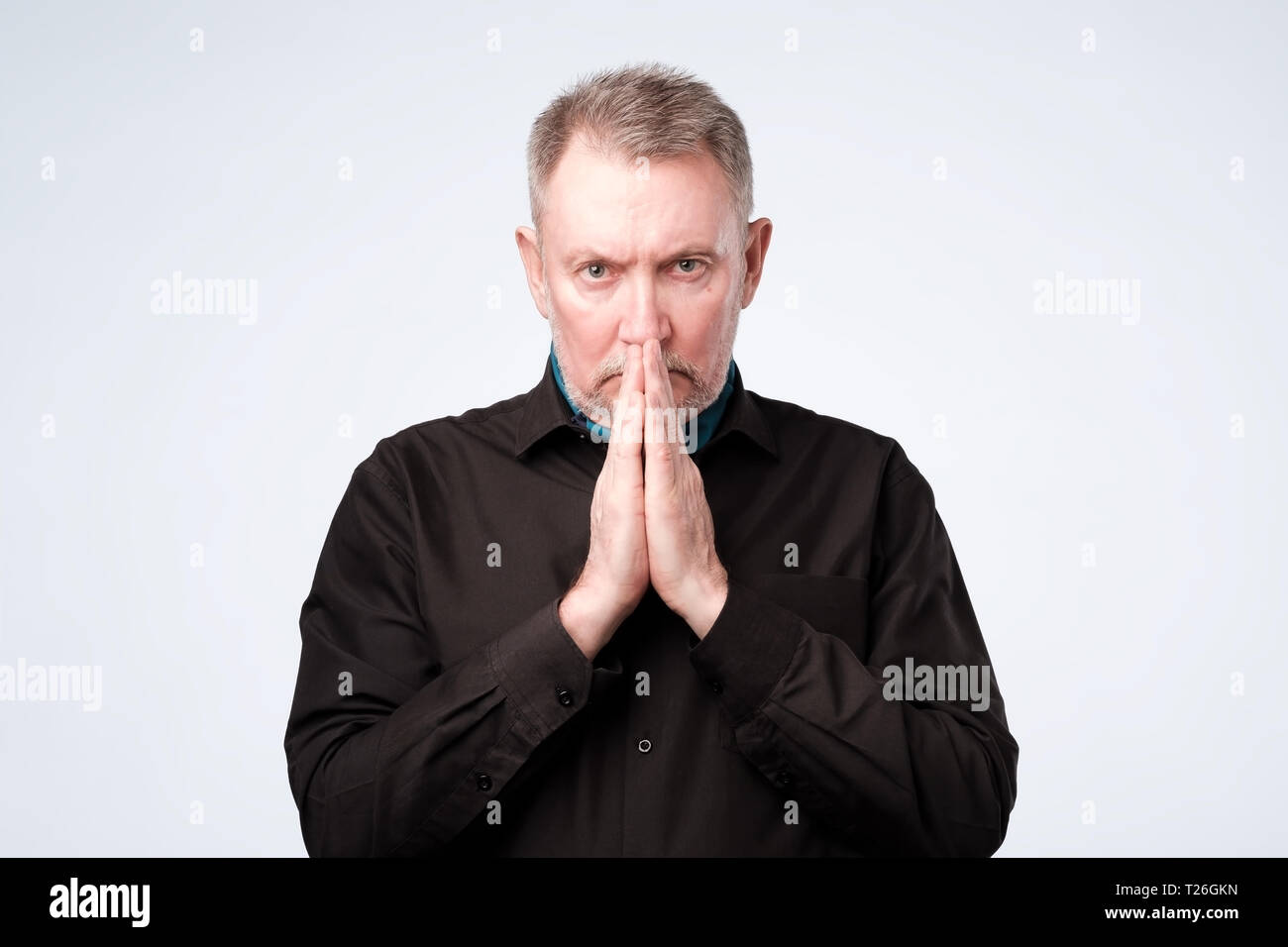 Senior vecchio uomo europeo mettere le mani insieme nella preghiera o nella meditazione, guardando la calma, in attesa di tutti i migliori Foto Stock