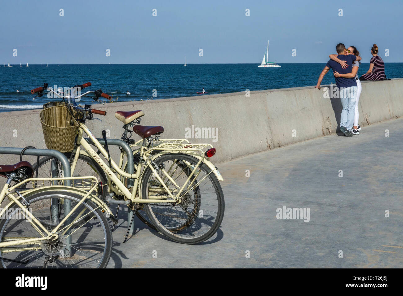 Giovani in amore giovane costeggiata sul molo, parcheggiato bici e barca a vela in background, Valencia Porto, Spagna Foto Stock