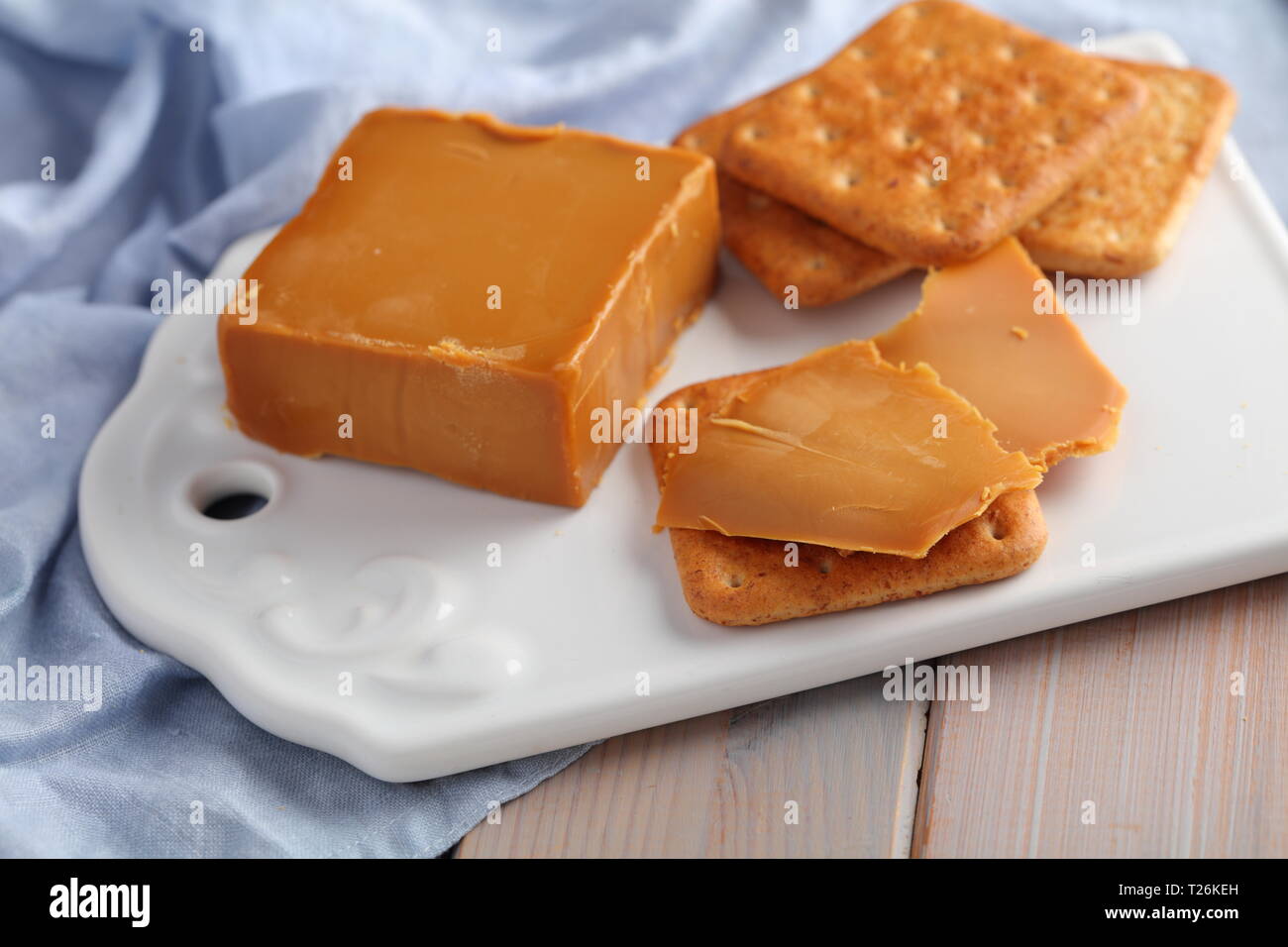 Crackers con Brunost, Norvegese Brown il formaggio su una ceramica tagliere Foto Stock