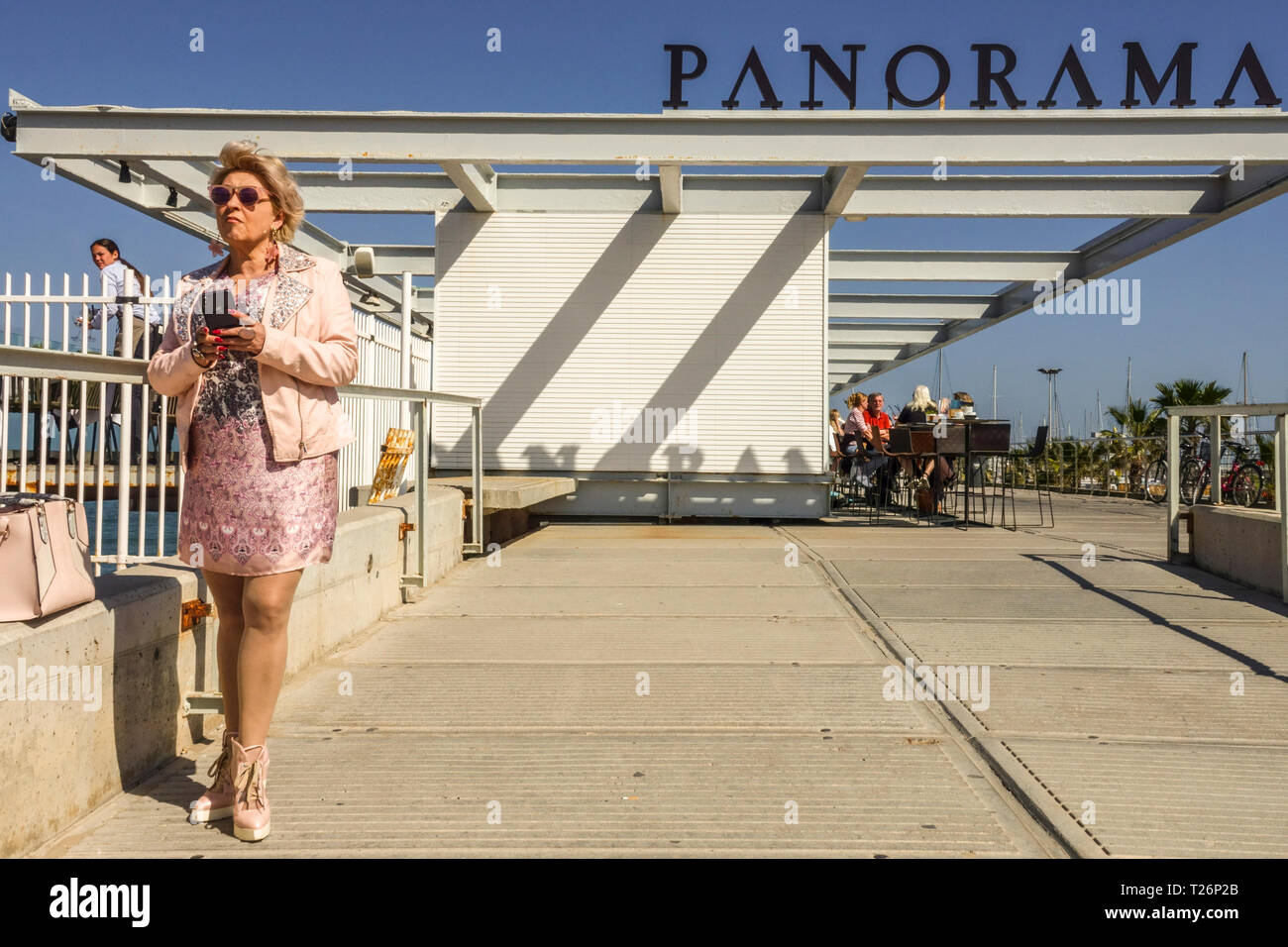 Donna in abito color beige in piedi nella parte anteriore del ristorante Panorama, il porto di Valencia Spagna Foto Stock