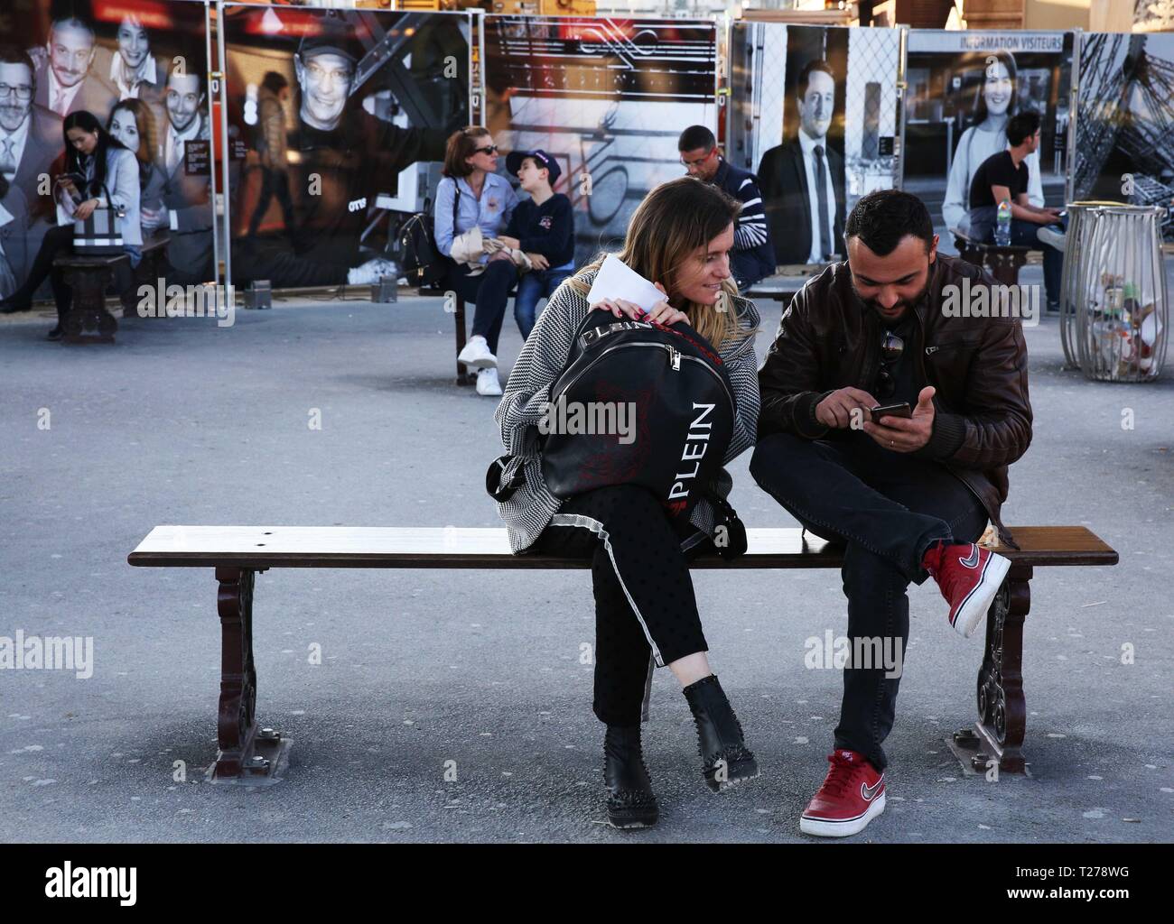 Parigi, Francia. 30 Mar, 2019. I turisti il resto in corrispondenza di una zona di una mostra fotografica dedicata alla gente che lavora per la Torre Eiffel a Parigi, Francia, il 30 marzo 2019. Una serie di eventi tra cui prestazioni, mostra fotografica e giochi di avventura si terrà dal 30 marzo per celebrare i cento trentesimo anniversario della Torre Eiffel. Credito: Gao Jing/Xinhua/Alamy Live News Foto Stock