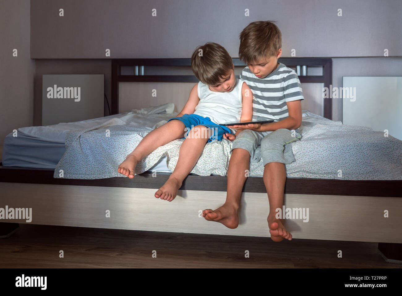 I bambini e i gadget. Due ragazzi con tavoletta sulle ginocchia. Home La scuola concetto. Preschooling sfondo. Home attività. Ricreazioni sfondo Foto Stock