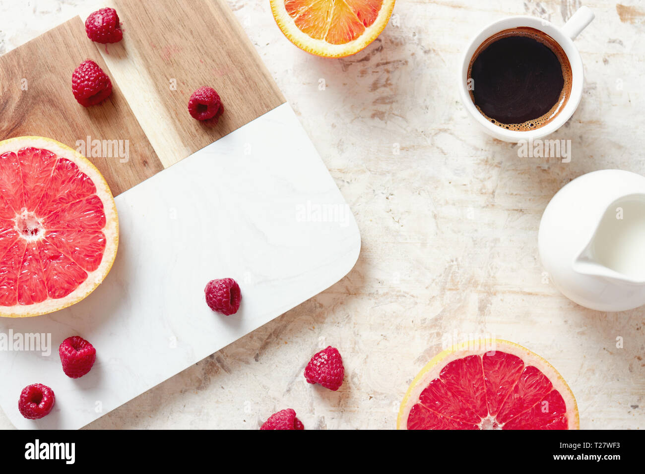 Chiusura del tavolo per la colazione con caffè fresco, pompelmi e pomeli, arance e lamponi. Foto Stock