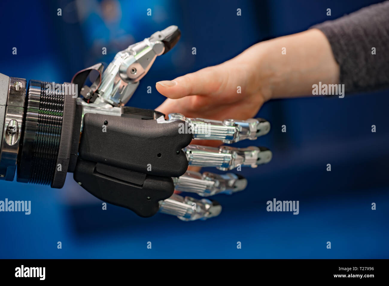 La mano di una imprenditrice stringono le mani con un robot androide. Il concetto di interazione umana con intelligenza artificiale. Foto Stock