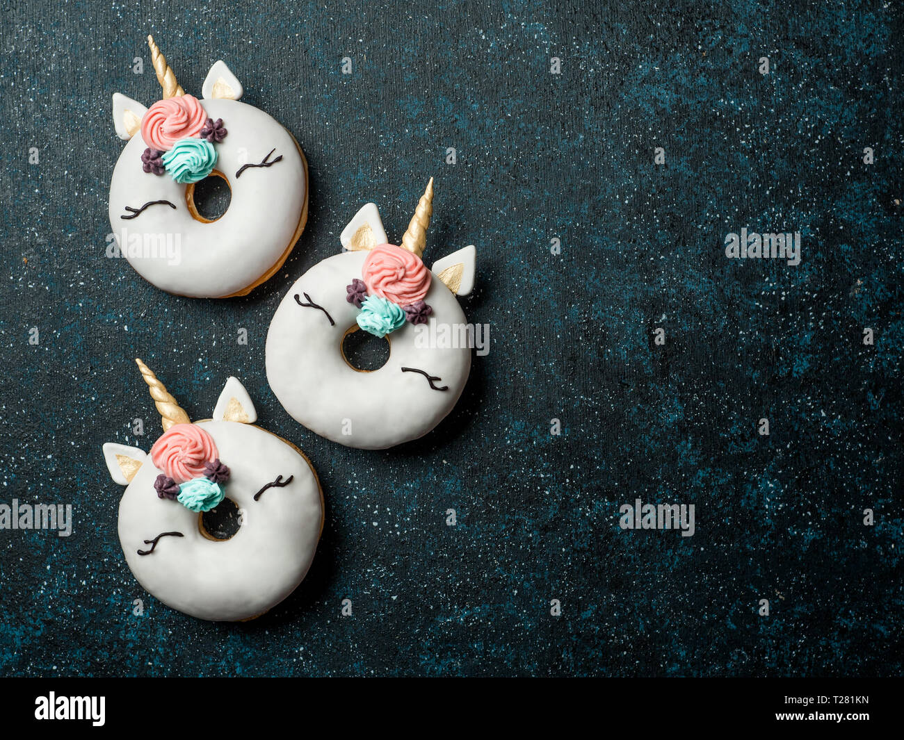 Unicorn ciambelle su sfondo scuro. Ciambella alla moda unicorn con smalto bianco. Vista superiore piatta o laici. Copia spazio per il testo. Foto Stock