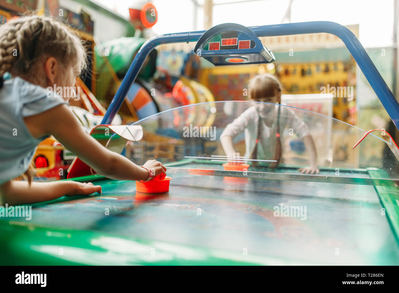 Due ragazze felici gioca air hockey in bambini di Game Center. Emozionato i bambini divertirsi sul parco giochi al chiuso. Bambini che giocano sulla macchina nel centro di divertimenti Foto Stock