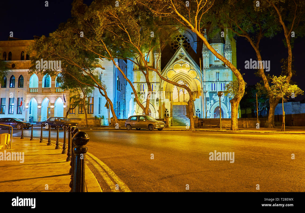 La passeggiata serale lungo la storica via Sarria con una vista sull'ex chiesa metodista dietro gli alberi, Floriana, Malta. Foto Stock