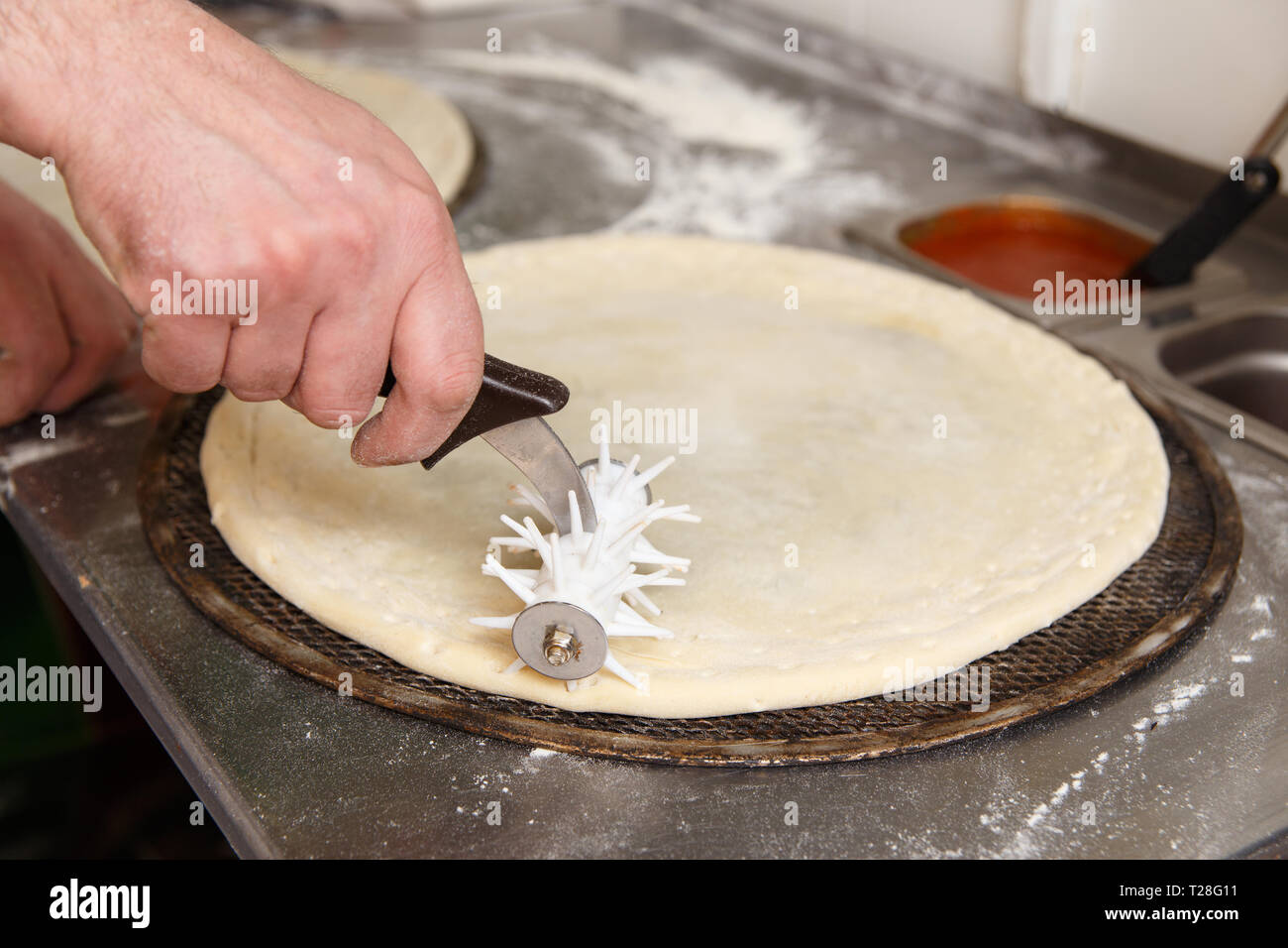 Cuocere forma un impasto base per pizza. La perforazione dei bordi di una  pizza a rullo Foto stock - Alamy