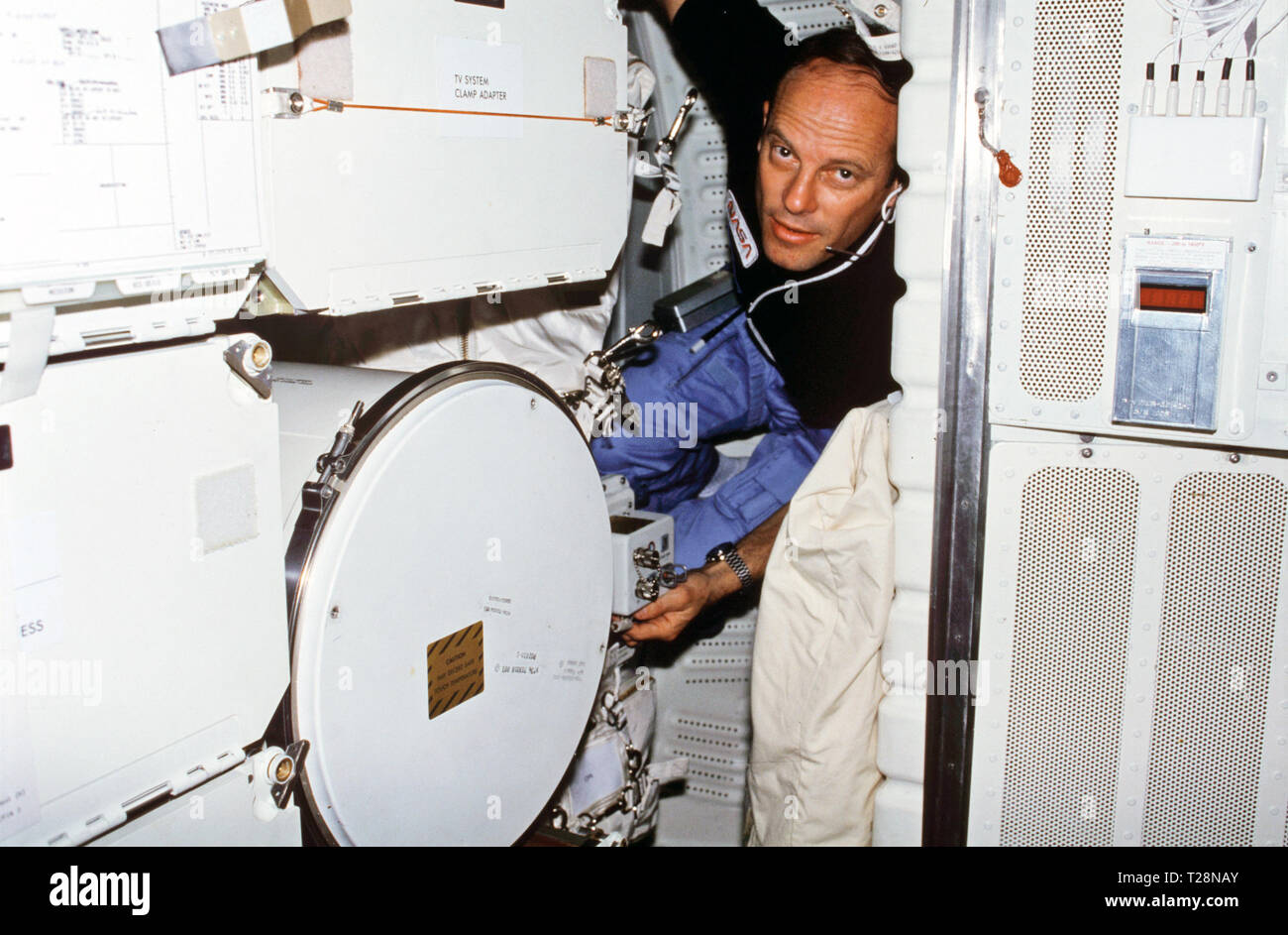 (22-30 marzo 1982) --- astronauta Jack Lousma R., STS-3 commander, indossando le comunicazioni di assemblaggio kit auricolare mini, regola i controlli sul lattice Monodisperse reattore (MLR) esperimento situato in avanti armadietti middeck MF57H e MF57K. Per raggiungere il supporto MLR electronics assy controlli, Lousma spreme in avanti tra gli armadietti e lo sviluppo di strumenti di volo (DFI) unità sulla paratia di dritta. Foto Stock