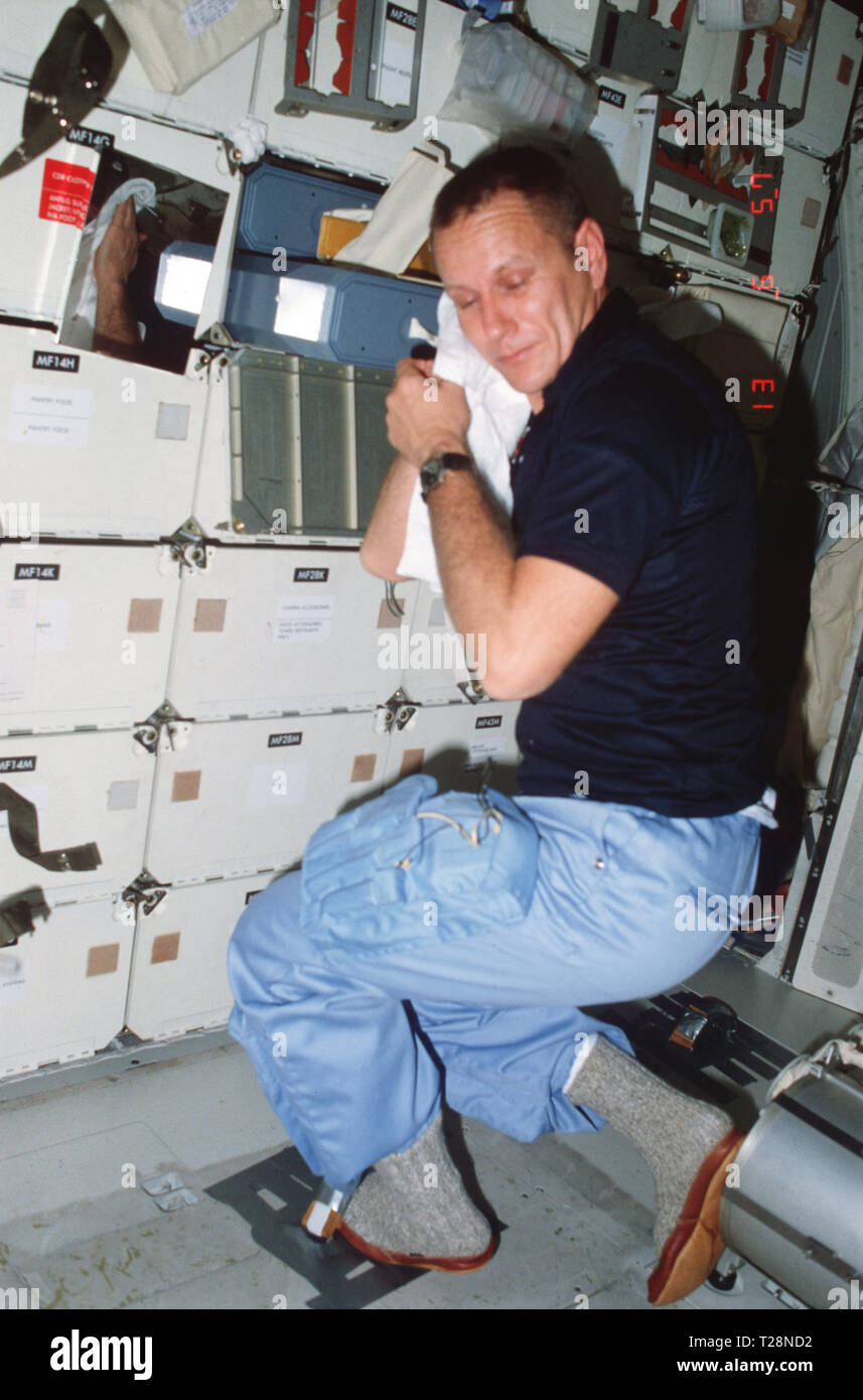 (11-16 nov. 1982) --- Sul middeck, astronauta Robert F. Overmyer, STS-5 pilota, asciugando il viso con un asciugamano da marcia avanti a vassoio singolo oggetto personale gavone di stivaggio, completa igiene personale attività (rasatura) e dimostra l'uso di attività intravehicular (IVA) ritenuta del piede sul pavimento. Foto Stock