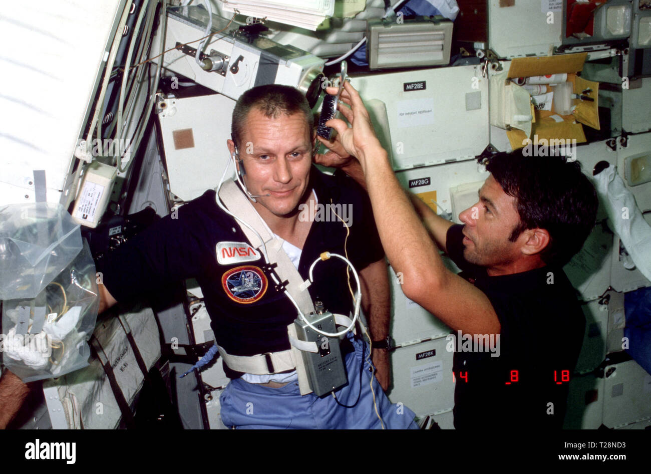 STS005-07-235 (11-16 nov. 1982) --- astronauta William B. Lenoir, lo specialista di missione per STS-5, utilizza le forbici e una spazzola per rifinire le basette di astronauta Robert F. Overmyer, pilota, nell'area middeck della terra-orbiting space shuttle Columbia. Un kit di apertura con forniture di igiene interno può essere visto attaccato ad uno dei gavone di stivaggio di porte in alto a destra. Foto Stock
