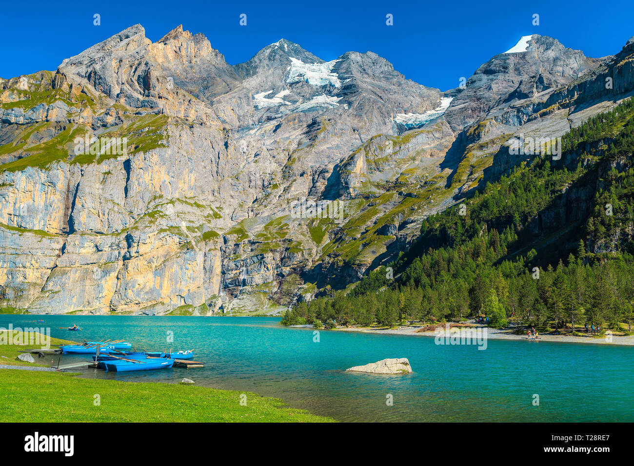 Famoso Viaggio e luogo di svago, splendido lago alpino e montagne innevate con barche colorate, Oeschinensee lago, Oberland bernese, Svizzera, Euro Foto Stock