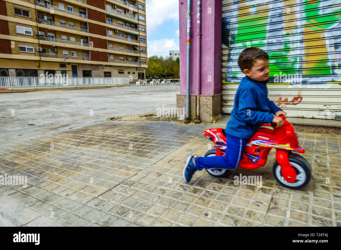 Bambino in motocicletta giocattolo di plastica, Valencia, Campanar barrio, Spagna bambino in giro Foto Stock