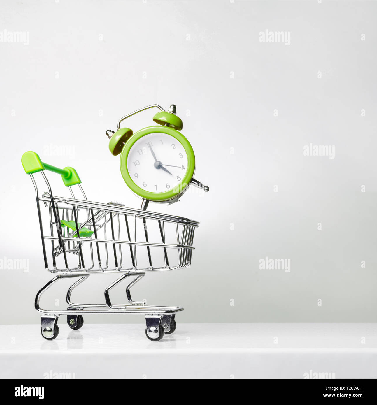 Sveglia e il carrello su una superficie. Tempo di acquistare. Spazio per il titolo e il testo. Foto Stock