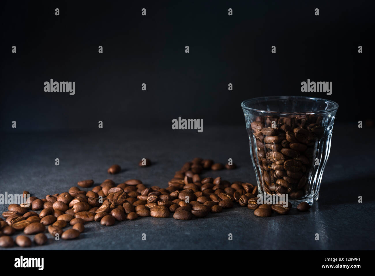 I chicchi di caffè in vetro su sfondo scuro con copia spazio, bassa immagine chiave Foto Stock