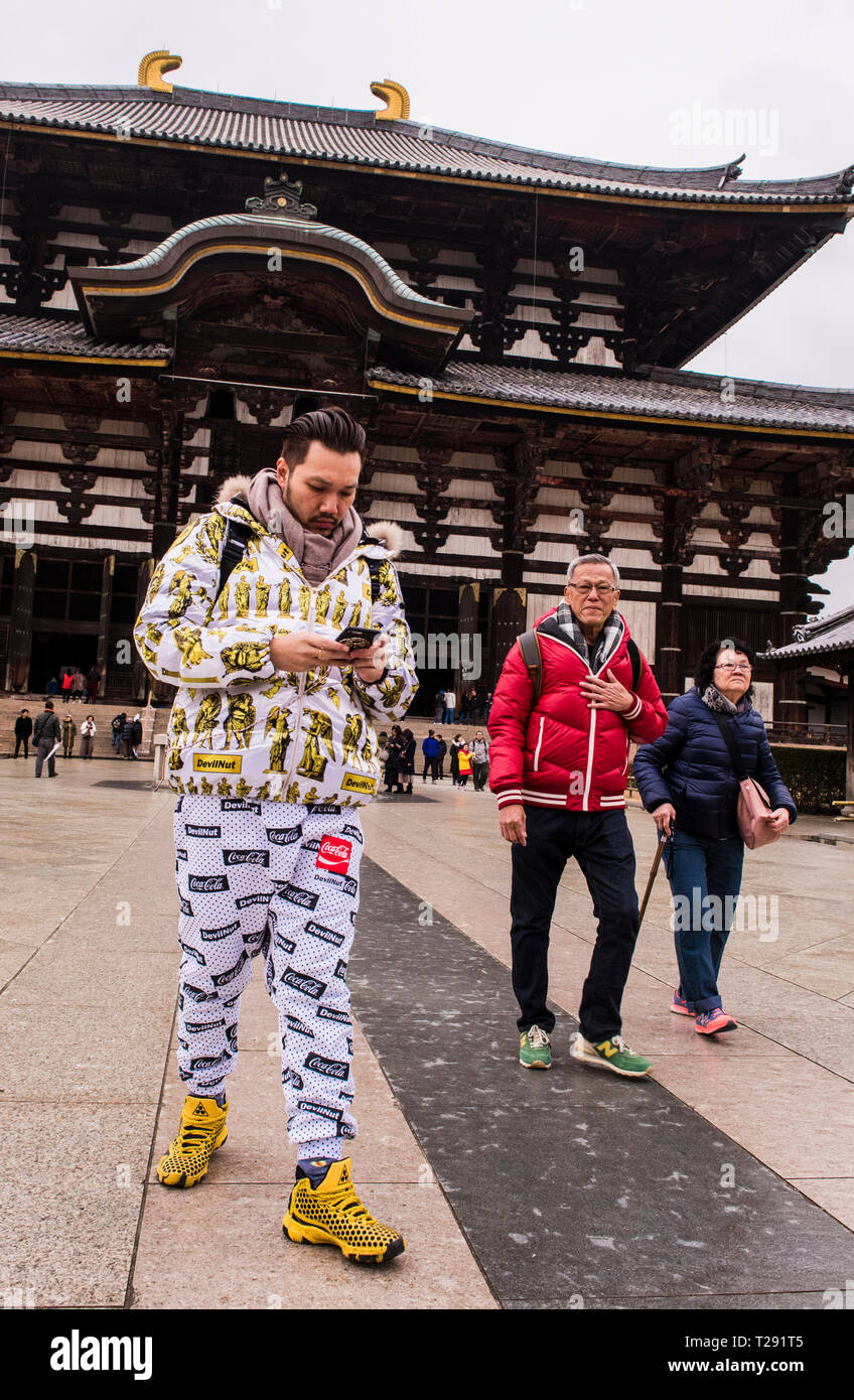 I turisti al di fuori del grande Budda sala del tempio Todai-Ji, uomo che indossa particolarmente outfit colorati, Nara, Giappone Foto Stock