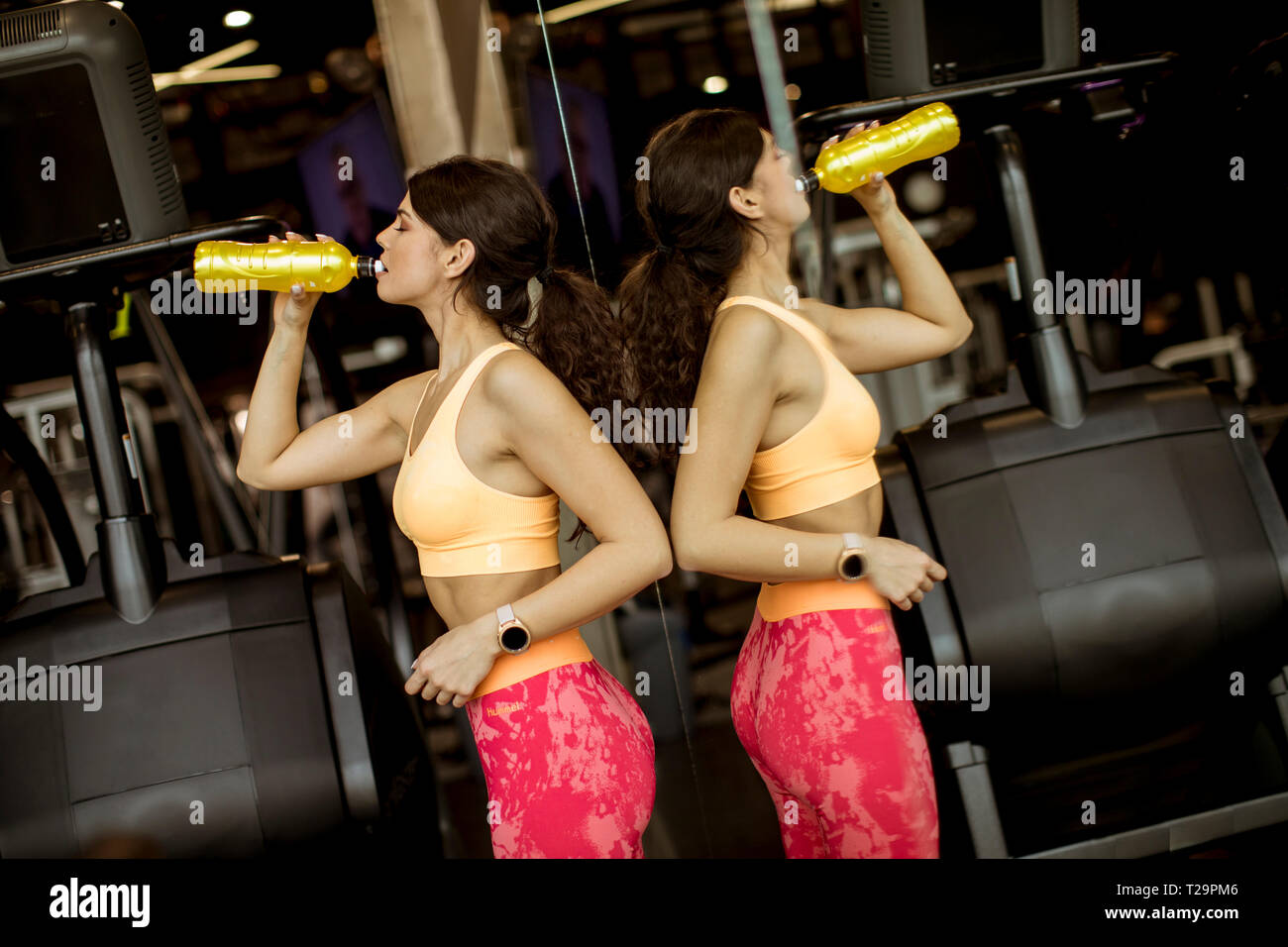 Donne sane in giallo sport shirt sono acqua potabile in palestra Foto Stock