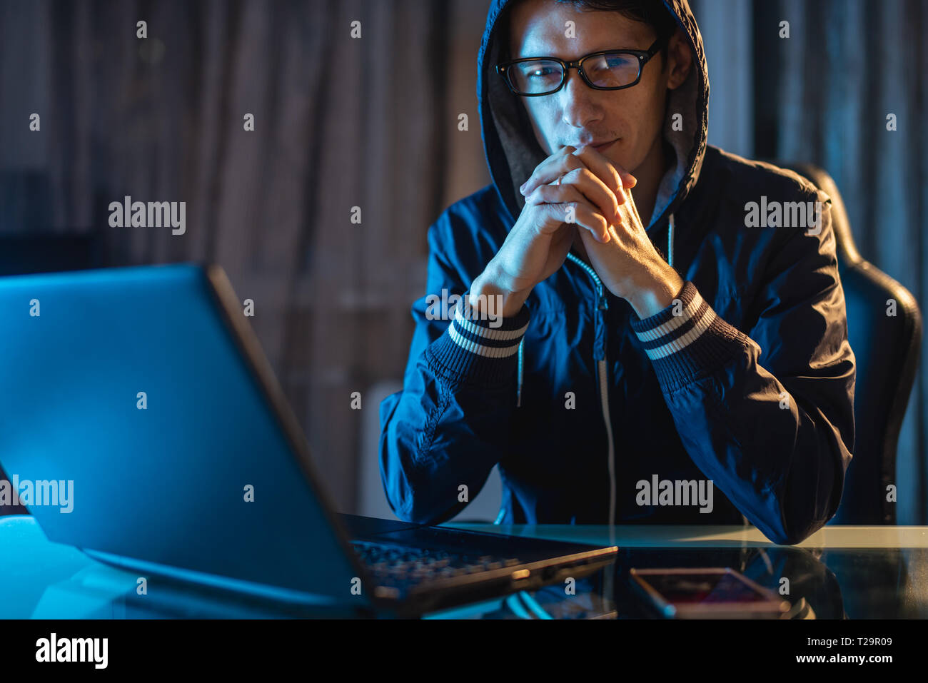 Maschio nel cofano cercando nella fotocamera. Attacchi di hacker e il furto di accedere ai database con password. Il concetto di sicurezza informatica Foto Stock