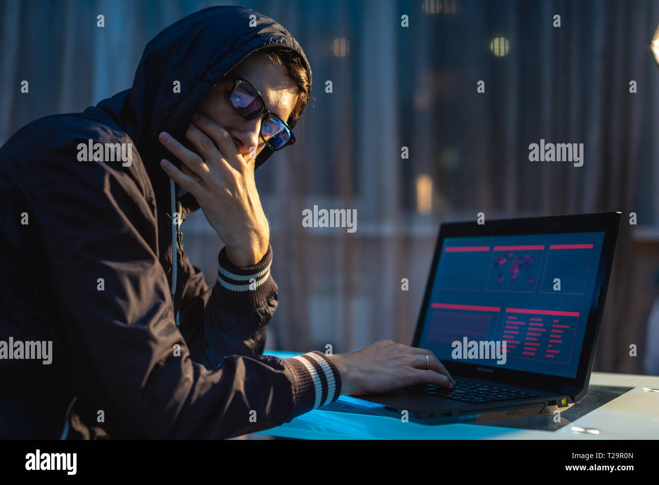 L'uomo nel cofano cercando nella fotocamera. Attacchi di hacker e il furto di accedere ai database con password. Il concetto di cyber security Foto Stock