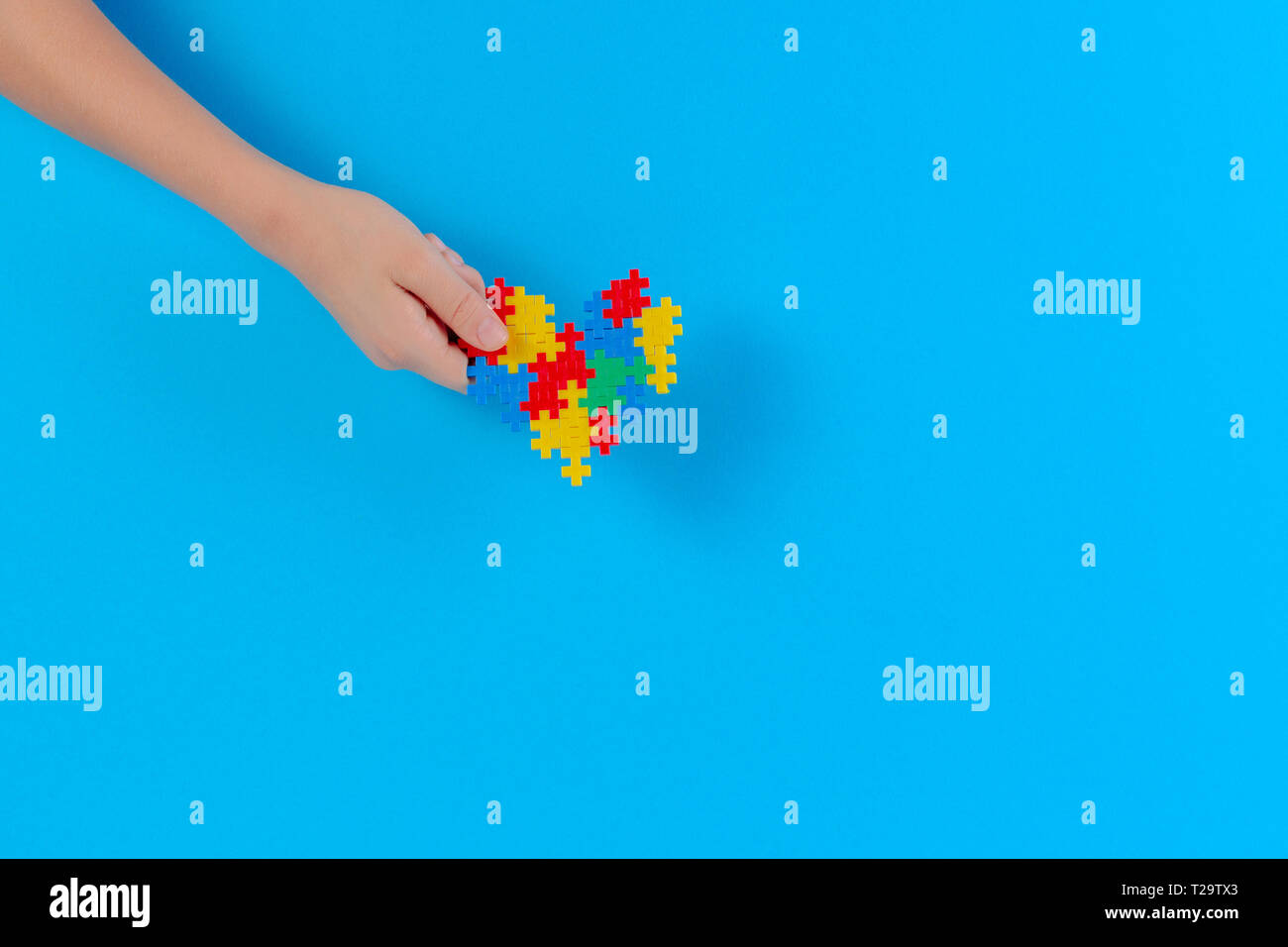 Bambino mano azienda cuore colorati su sfondo blu. Mondo autismo consapevolezza giorno di concetto Foto Stock
