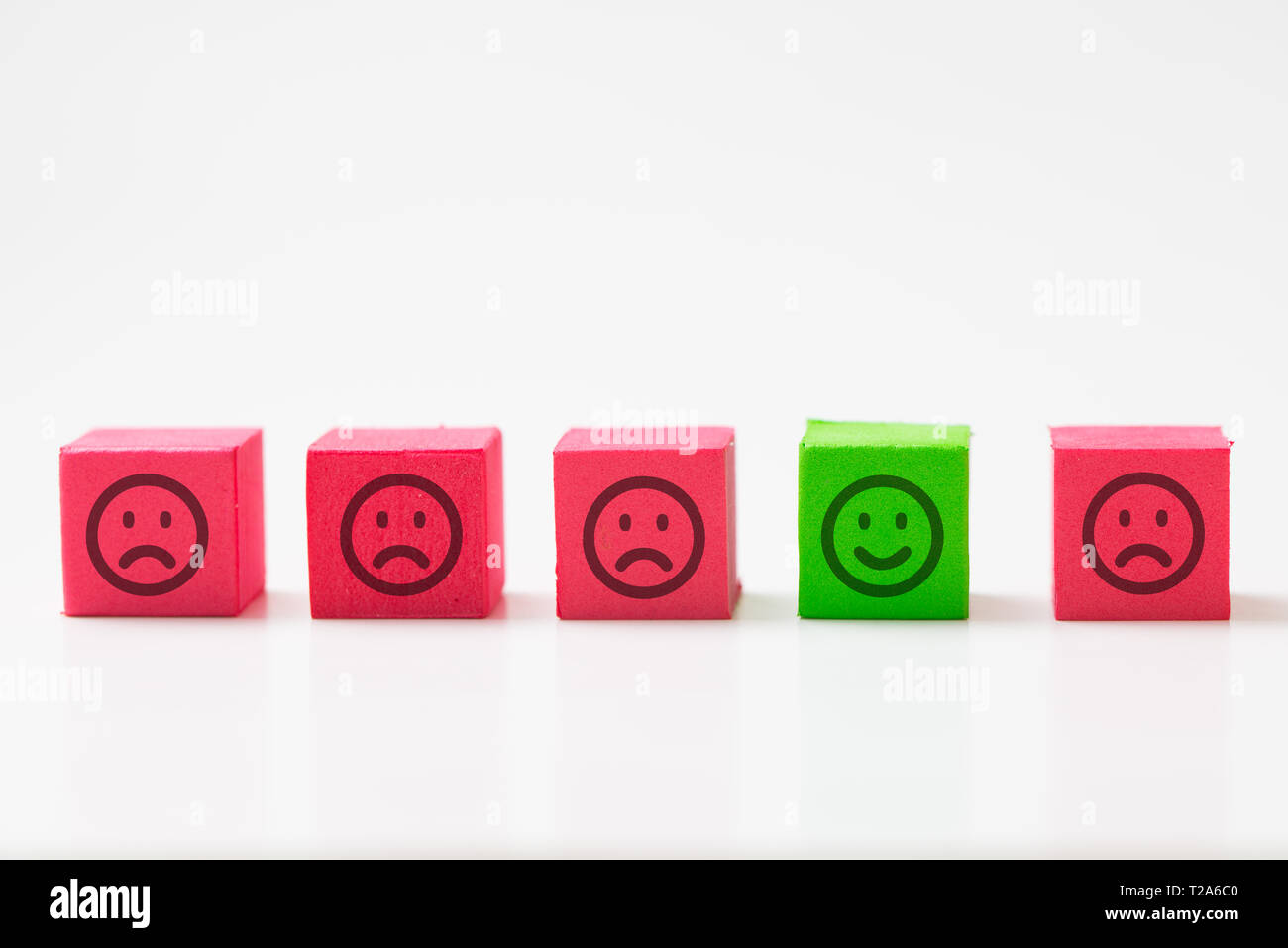 Unico, ottimista, felicità, il concetto di differenza utilizzando una singola faccia felice tra molte facce tristi. Foto Stock