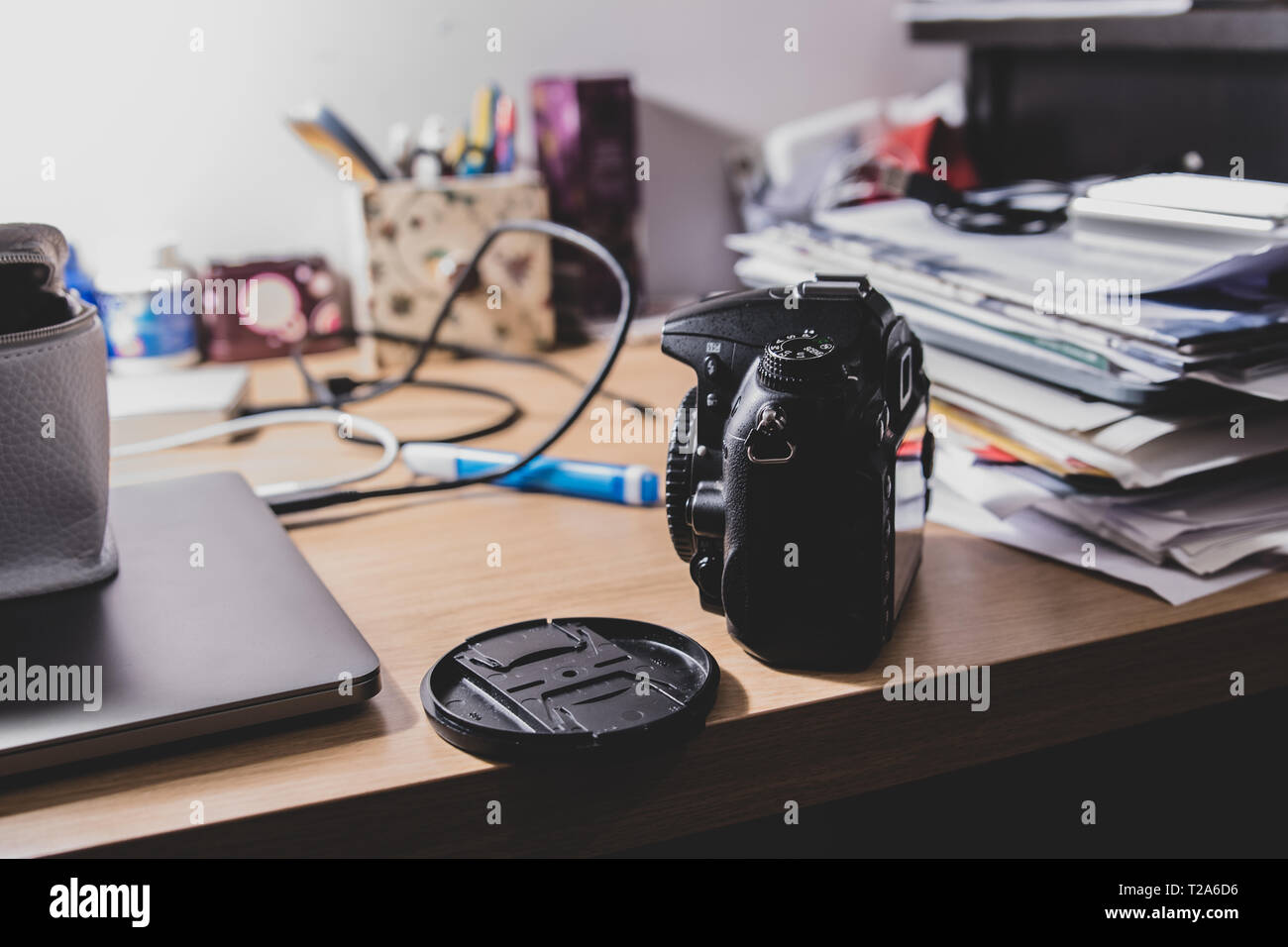 Una generica macchina fotografica Nikon senza branding visibile su un tavolo sotto la lampada da tavolo presso l'ufficio domestico o di studio di un blogger. Foto Stock