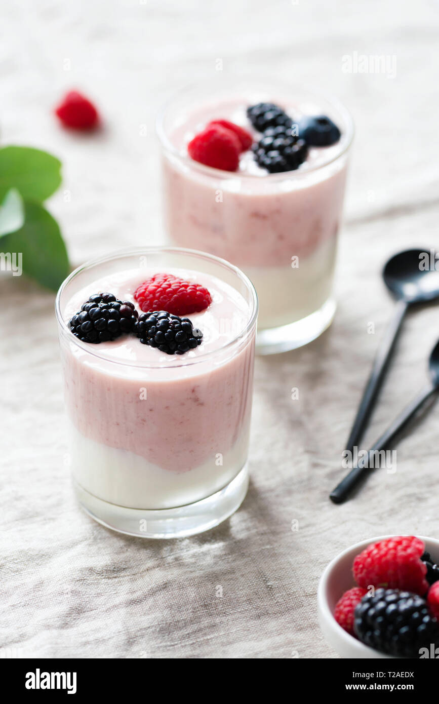 Frutta e bacche di yogurt in coppa di vetro su lino textle. Una sana prima colazione, snack e pasti Foto Stock