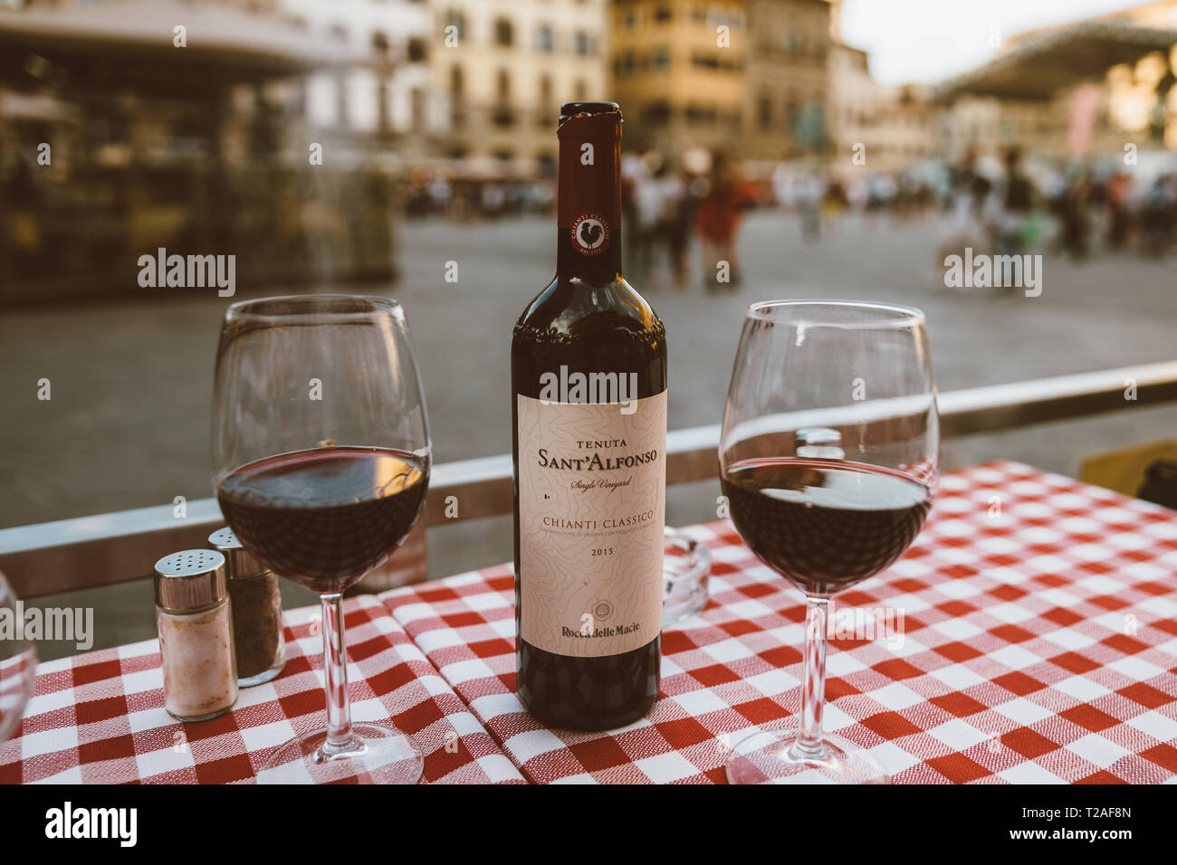 Firenze, Italia - 24 Giugno 2018: primo piano della bottiglia di vino rosso Sant Alfonso Chianti Classico e i bicchieri sul tavolo del ristorante sullo sfondo di Piazza d Foto Stock