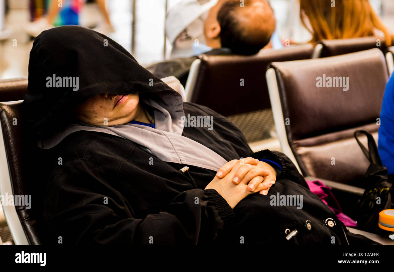 Donna che Dorme sulla sedia, cofano che copre il viso, all'Aeroporto di Hong Kong, Hong Kong Foto Stock