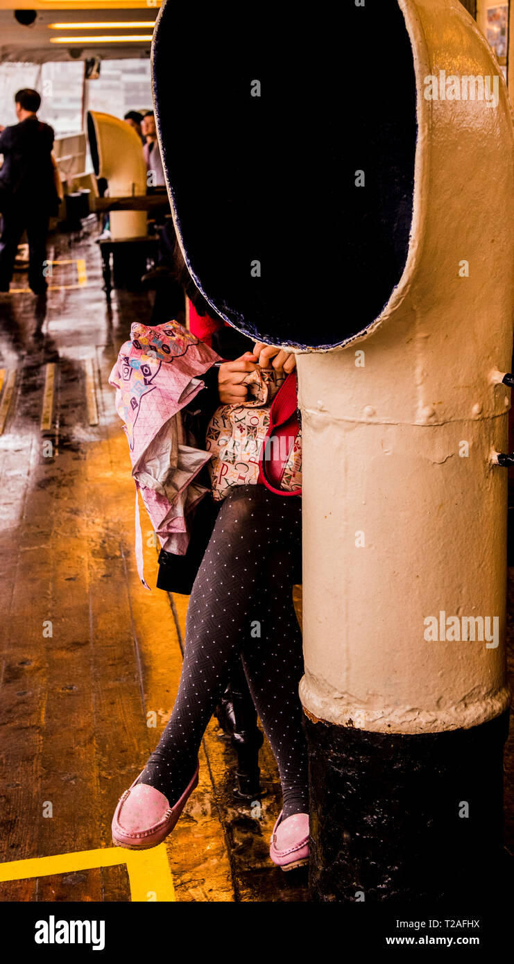 Donna seduta sul traghetto Star, parzialmente oscurata da un imbuto, Hong Kong Foto Stock